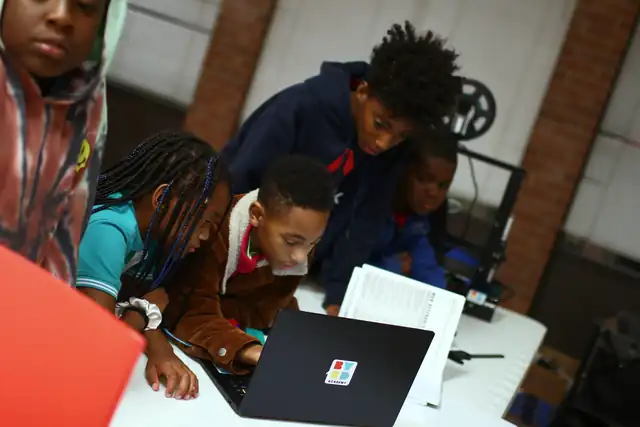 Students crowd a laptop to see their design