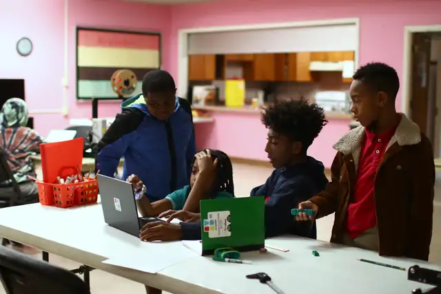 Students work at laptops around a table