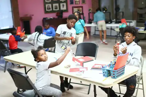 Children build at tables in a community center