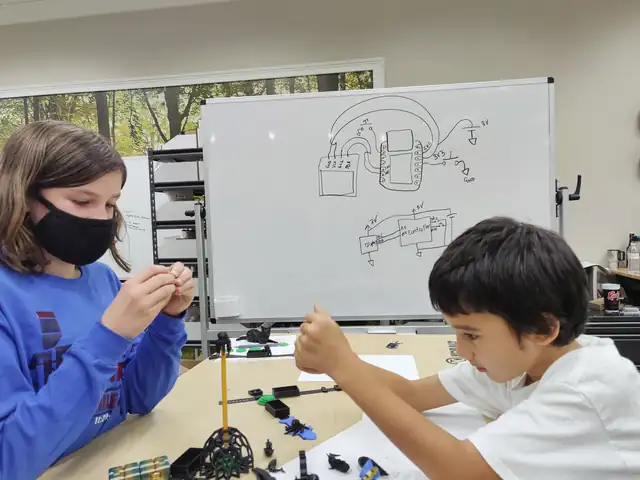 Two students wire circuits across the table