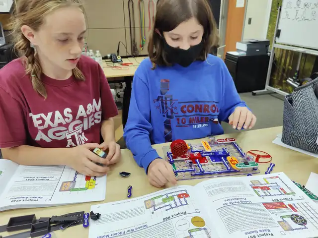 Two students build circuits side by side