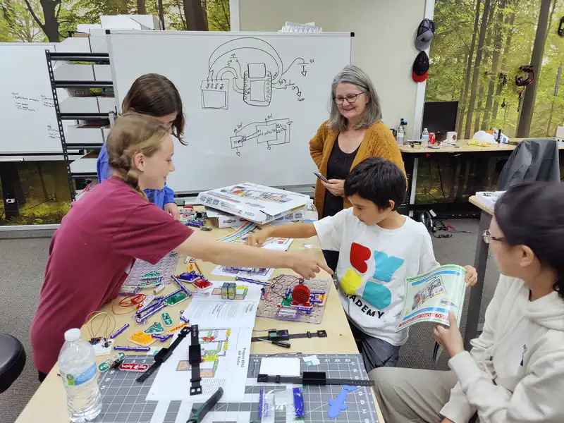A table of students and a mentor building circuits