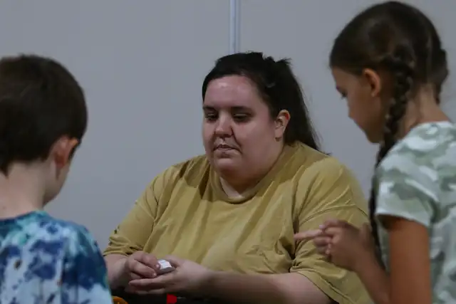 A mentor works with a young builder at a table during a competition
