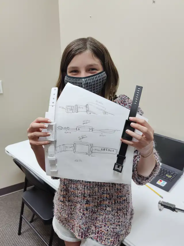 A student holds up her design and the band she printed