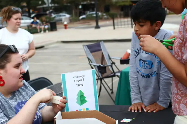 A mentor holds up a challenge card for a visitor