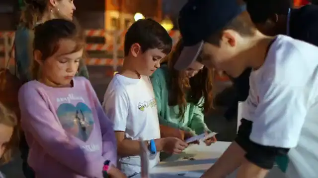 Children build their bookmarks at the street table at dusk