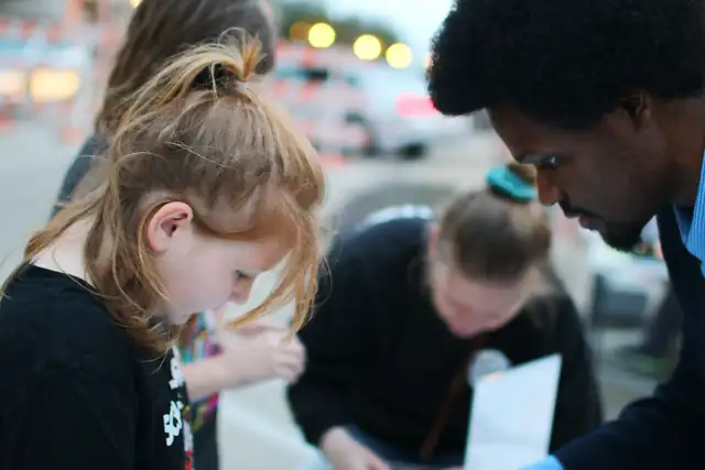 A girl concentrates on her build as a mentor guides her