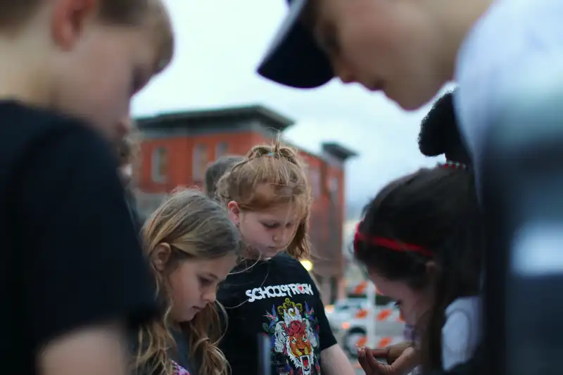 Girls bend over their light-up bookmarks at the street table