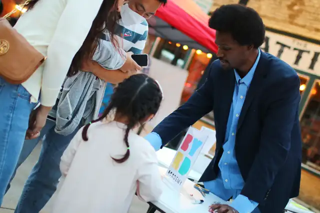 A mentor leans in to help a young builder