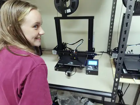 A student smiles beside the 3D printer making her design