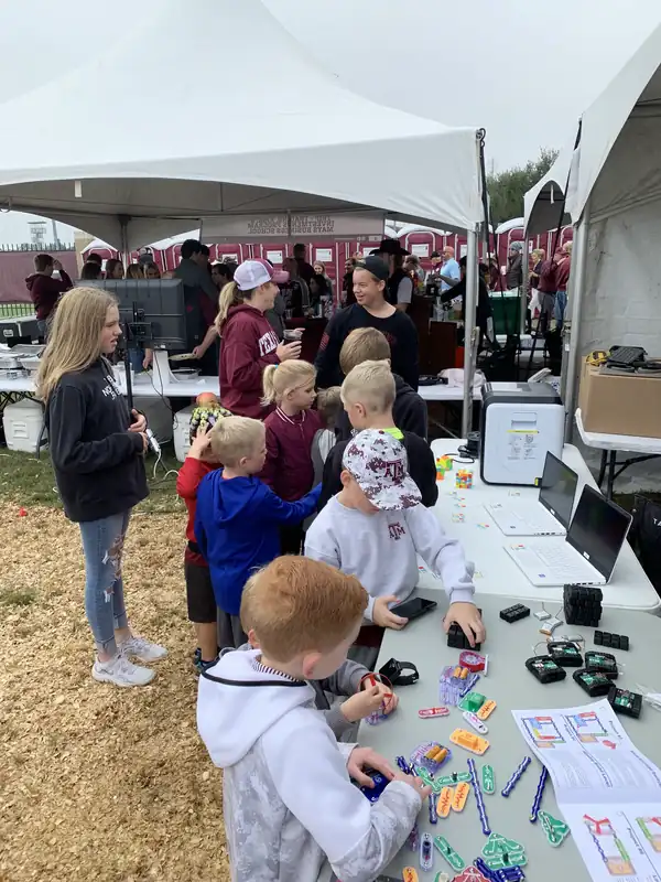 Children build circuits at a Byrd Zone table under a tailgate tent